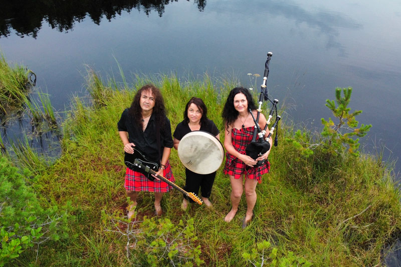 Verehara ... drei Personen mit Musikinstrumenten stehen am Ufer eines Sees